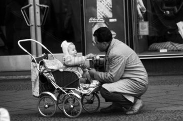 Berlin  Deutsche Demokratische Republik  Vater kniet vor seinem im Kinderwagen sitzenden Kind