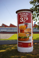 Aurich  Deutschland  eine alte  schiefe Litfasssaeule mit Werbung fuer McDonalds