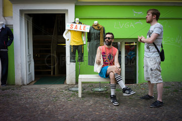 Berlin  Deutschland  zwei Maenner sitzen vor einem Laden in der Kastanienallee