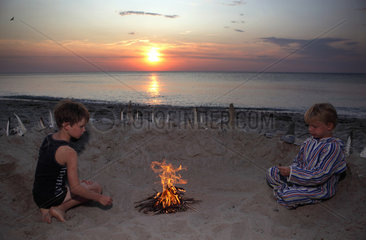 Kaegsdorf  Deutschland  Kinder sitzen abends an einem Lagerfeuer am Strand