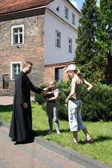Kalisch  Polen  Geistlicher unterhaelt sich mit zwei Maedchen