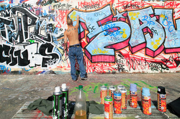 Berlin  Deutschland  Mann besprueht einen Mauerabschnitt