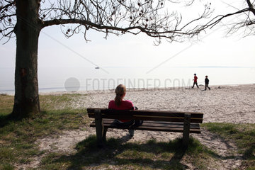Klink  Deutschland  eine Frau sitzt auf einer Bank am Strand und beobachtet ihre Kinder