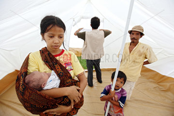 Sungai Rambai  Indonesien  eine Frau mit einem Baby im Arm in einer Notunterkunft