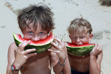 Santa Margherita di Pula  Italien  Jungen beissen gierig in ein Stueck Wassermelone