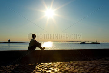 Assens  Daenemark  eine Frau sitzt an der Strandpromenade und geniesst den Ausblick