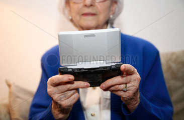 Berlin  Deutschland  eine alte Frau spielt mit einem Nintendo DS