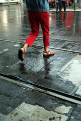 Berlin  Passant geht ueber nasse Strasse