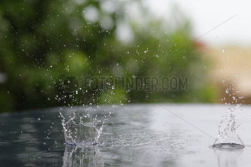 Le Barcares  Frankreich  Regentropen fallen auf eine nasse Tischplatte und erzeugen Einschlagskrater