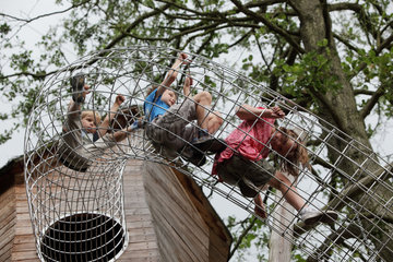 Marlow  Deutschland  Kinder auf einem Spielplatz klettern durch eine Gitterroehre