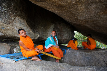 Koh Kong  Kambodscha  buddhistische Moenche sitzen unter einem Felsen
