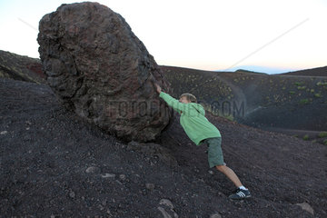 Catania  Italien  Sisyphusarbeit  ein Junge versucht einen Lavastein einen Abhang nach oben zu rollen