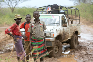 Kakuma  Kenia - Auf einer Landstrasse ausserhalb des Fluechtligsklagers Kakuma stehen drei Jungen vor einem Pickup.