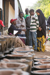 Kakuma  Kenia - Im Fluechtlingslager Kakuma verteilt ein lokaler Mitarbeiter Kochoefen an junge Fluechtlinge.