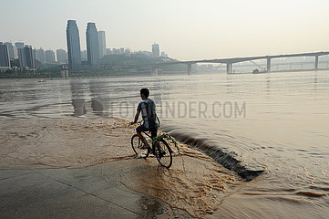 Chongqing  China  Ein Radfahrer im Jangtse Fluss
