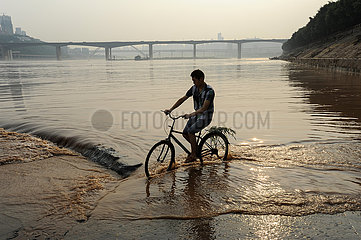 Chongqing  China  Ein Radfahrer im Jangtse Fluss