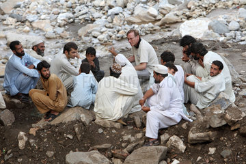 Kokarai  Pakistan  Mitarbeiter einer Hilfsorganisation im Gespraech mit Bewohnern eines Dorfes