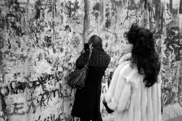 Berlin  Deutschland  Mann filmt mit der Kamera durch ein Loch in der Mauer