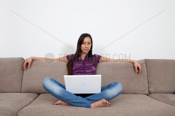 Essen  Deutschland  Frau mit Laptop auf dem Sofa