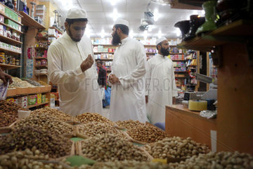Dubai  Vereinigte Arabische Emirate  Mann betrachtet in einem Lebensmittelgeschaeft kritisch eine Nuss