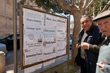 Modica  Italien  Sizilianer stehen vor einer Tafel fuer Todesanzeigen