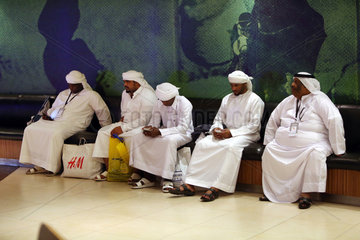 Dubai  Vereinigte Arabische Emirate  Maenner in Landestracht sitzen auf einer Bank