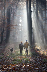 Neu Kaetwin  Deutschland  Kinder laufen mit einem Hund im Streiflicht durch einen Wald