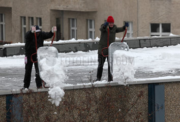 Berlin  Deutschland  Maenner entfernen Schnee von einem Flachdach