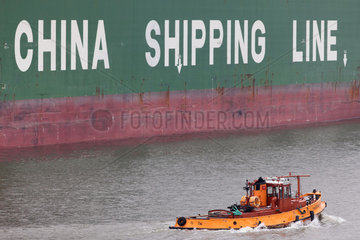 Hamburg  Deutschland  Hafenschlepper vor der Bordwand eines Containerschiffes