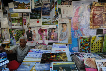 Yangon  Myanmar  Strassenhaendler verkauft Kalender und Poster