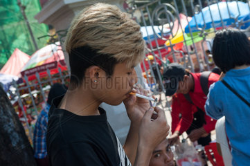 Yangon  Myanmar  Jugendlicher zuendet sich eine Zigarette an