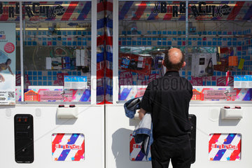 Berlin  Deutschland  Mann versucht an einem Barbercut Automaten ein Handy zu gewinnen