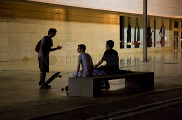 Barcelona  Spanien  Jugendliche abends auf der Bank vor einem Kaufhaus