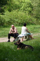 Kalisch  Polen  zwei Menschen und ein Deutscher Schaeferhund auf einer Parkbank