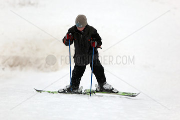 Berlin  Deutschland  Junge laeuft auf Skiern einen Hang hinauf