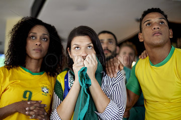 Brazilian football supporters anxiously watching match in bar