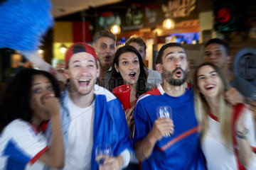 French football fans watching soccer match on television at pub
