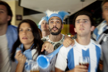 Argentinian football supporters anxiously watching match in bar