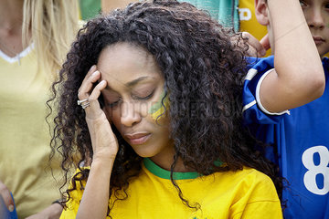 Woman holding head in disappointment at Brazilian football match