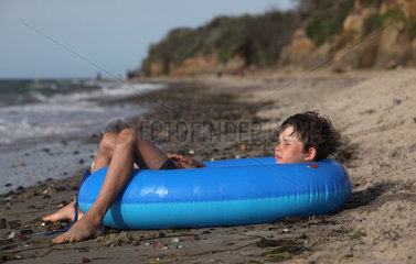 Kaegsdorf  Deutschland  Junge liegt schlafend in einem Schlauchboot am Strand