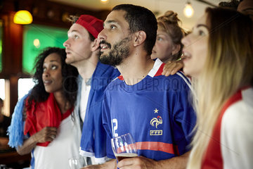 French football supporters watching match in bar
