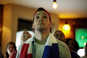 French football fan watching match in bar