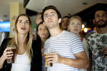 Sports enthusiasts watching match in bar