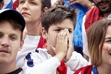 Young football fan covering face during football match