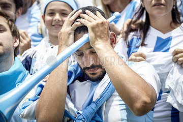 Argentinian football fan holding head in disappointment at match