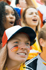 German football fan watching match with face painted in support