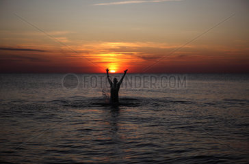 Kaegsdorf  Deutschland  Silhouette  ein Mann springt bei Sonnenuntergang aus dem Meer