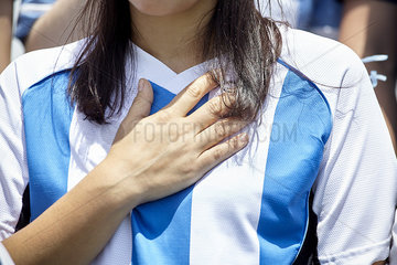 Argentinian football supporter holding hand over heart at match  close-up