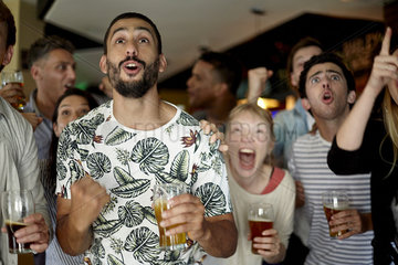 Sports enthusiasts excitedly watching match in bar