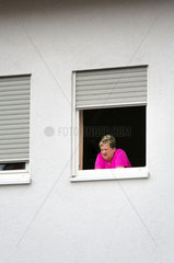 Beckingen  Deutschland  Frau mittleren Alters schaut aus dem Fenster